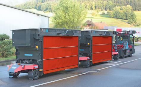 Vollautomatisierter und autonomer Outdoor-Routenzug Factory Train von Neumaier Industry mit Teleskopgabel-Warenträger für die automatisierte Aufnahme und Abgabe von Ladungsträgern auf/von Übergabestationen oder direkt auf den bzw. vom Boden